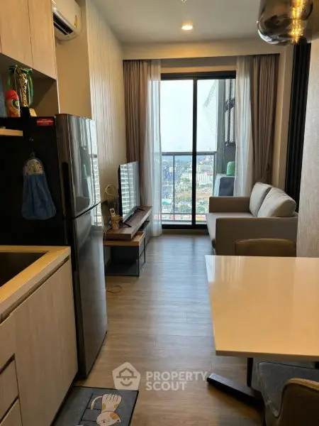 Modern living room with city view, sleek furniture, and open kitchen layout in a high-rise apartment.