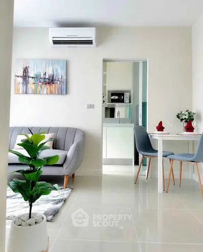 Modern living room with stylish decor and open kitchen layout, featuring sleek furniture and vibrant artwork.