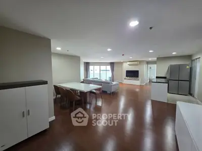 Spacious open-plan living room with modern kitchen and dining area, featuring sleek furniture and ample natural light.