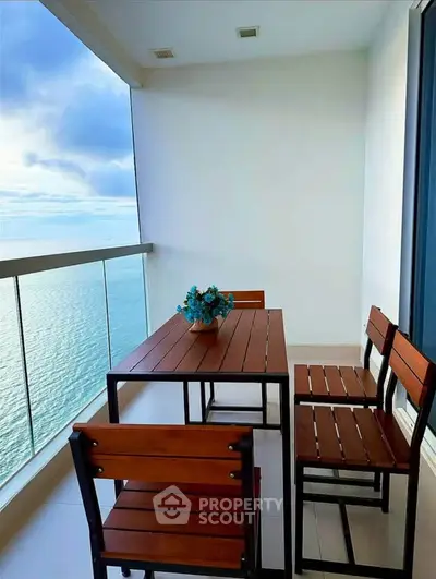 Stunning oceanfront balcony with modern wooden furniture and breathtaking sea view.