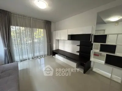 Spacious modern living room with sleek built-in storage and large window for natural light.