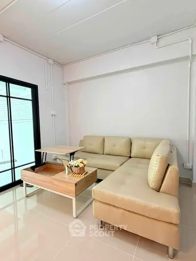 Modern living room with beige sectional sofa and sleek coffee table in a bright, minimalist space.
