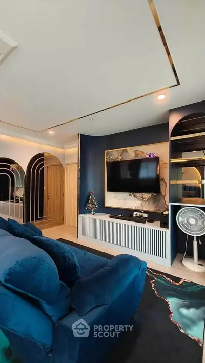 Luxurious living room with modern decor, plush blue sofa, and wall-mounted TV in stylish apartment.