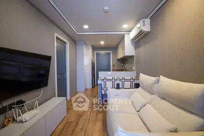 Modern living room with open kitchen, featuring sleek design and cozy seating area.