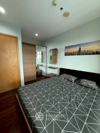 Modern bedroom with geometric bedding and cityscape artwork, featuring wooden flooring and built-in wardrobe.