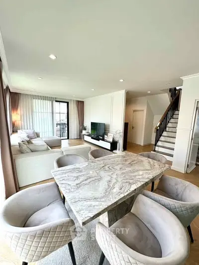 Spacious modern living room with elegant dining area and staircase in luxury home.