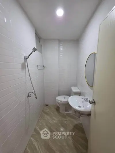 Compact bathroom with shower, toilet, and sink in a modern apartment.