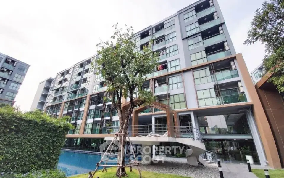 Modern apartment building with pool and lush greenery, offering a serene urban living experience.