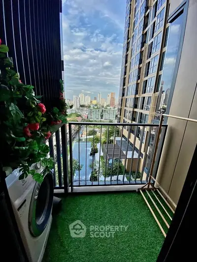 Charming balcony with artificial grass and city view, featuring a washing machine and lush greenery.