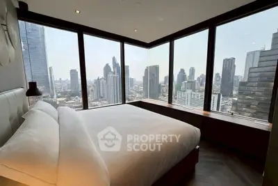 Luxurious bedroom with panoramic city skyline view from floor-to-ceiling windows.