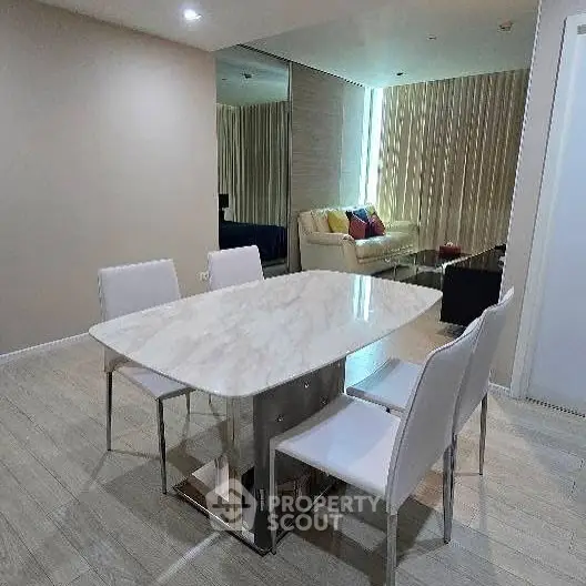 Modern dining area with marble table and sleek white chairs in a stylish apartment.