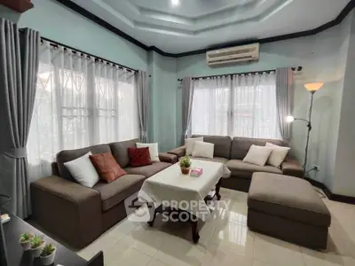 Spacious living room with elegant decor and ample natural light, featuring a cozy sectional sofa and stylish curtains.