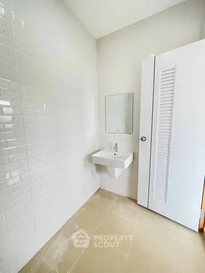 Modern minimalist bathroom with white tile walls and sleek sink design.