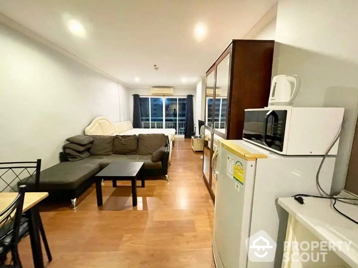 Modern studio apartment with open layout, featuring cozy living area and compact kitchen.