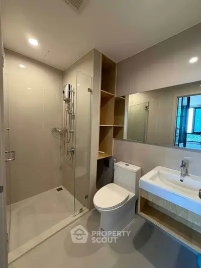 Modern bathroom with glass shower, sleek sink, and toilet in a contemporary apartment.