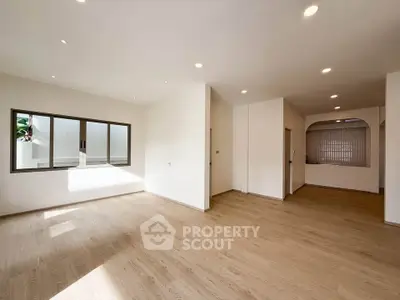 Spacious modern living room with wooden flooring and ample natural light.