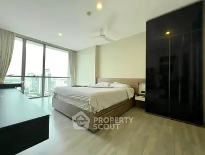 Spacious bedroom with large windows and city view, featuring modern furniture and sleek design.