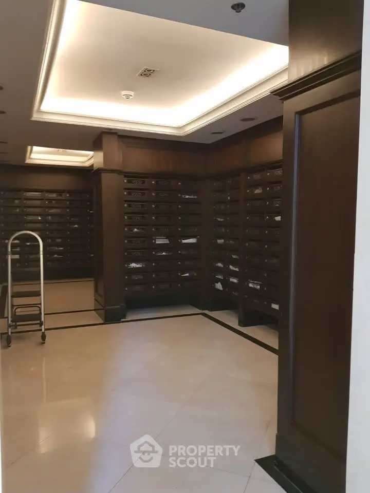 Elegant building lobby with wooden paneling and mailboxes, showcasing a sophisticated entrance area.
