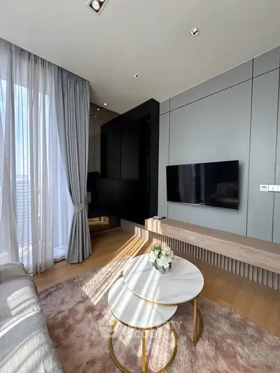 Modern living room with stylish decor, large window, and wall-mounted TV in a chic apartment.