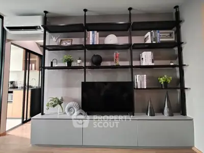 Modern living room with stylish shelving and TV unit, open kitchen view.