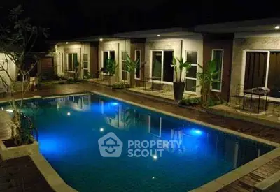 Luxurious night view of a modern villa with illuminated swimming pool and elegant patio.