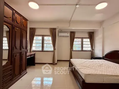 Spacious bedroom with elegant wooden furniture and large windows for natural light.