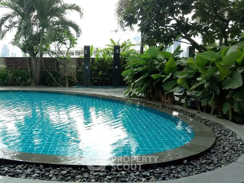 Luxurious outdoor pool surrounded by lush greenery in a modern residential complex.