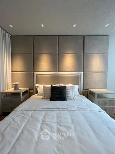 Luxurious bedroom with elegant lighting and modern decor, featuring a plush headboard and stylish bedside tables.