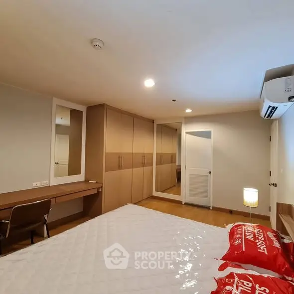 Spacious bedroom with modern furniture and ample storage in a cozy apartment.