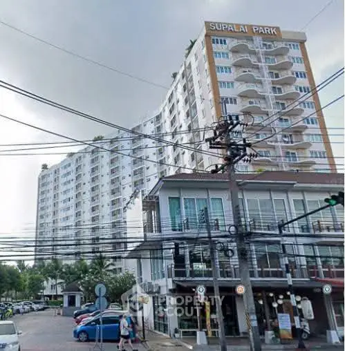 Modern high-rise condominium with urban street view and lush greenery.