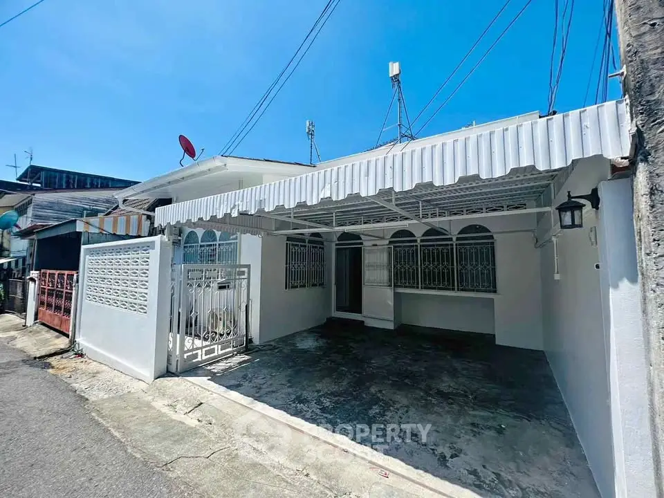 Charming single-story home with gated driveway and awning, perfect for cozy living.