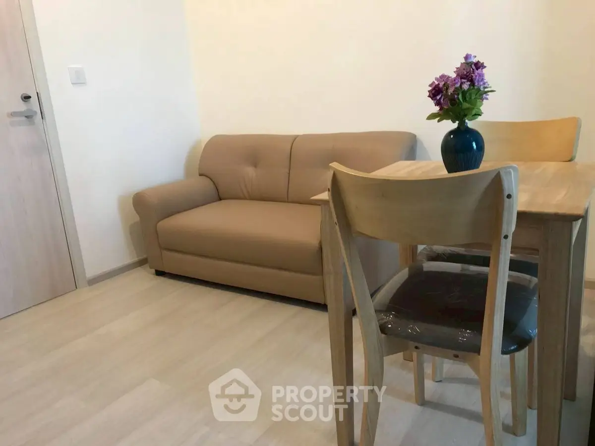 Cozy living room with beige sofa and wooden dining set, perfect for small apartments.