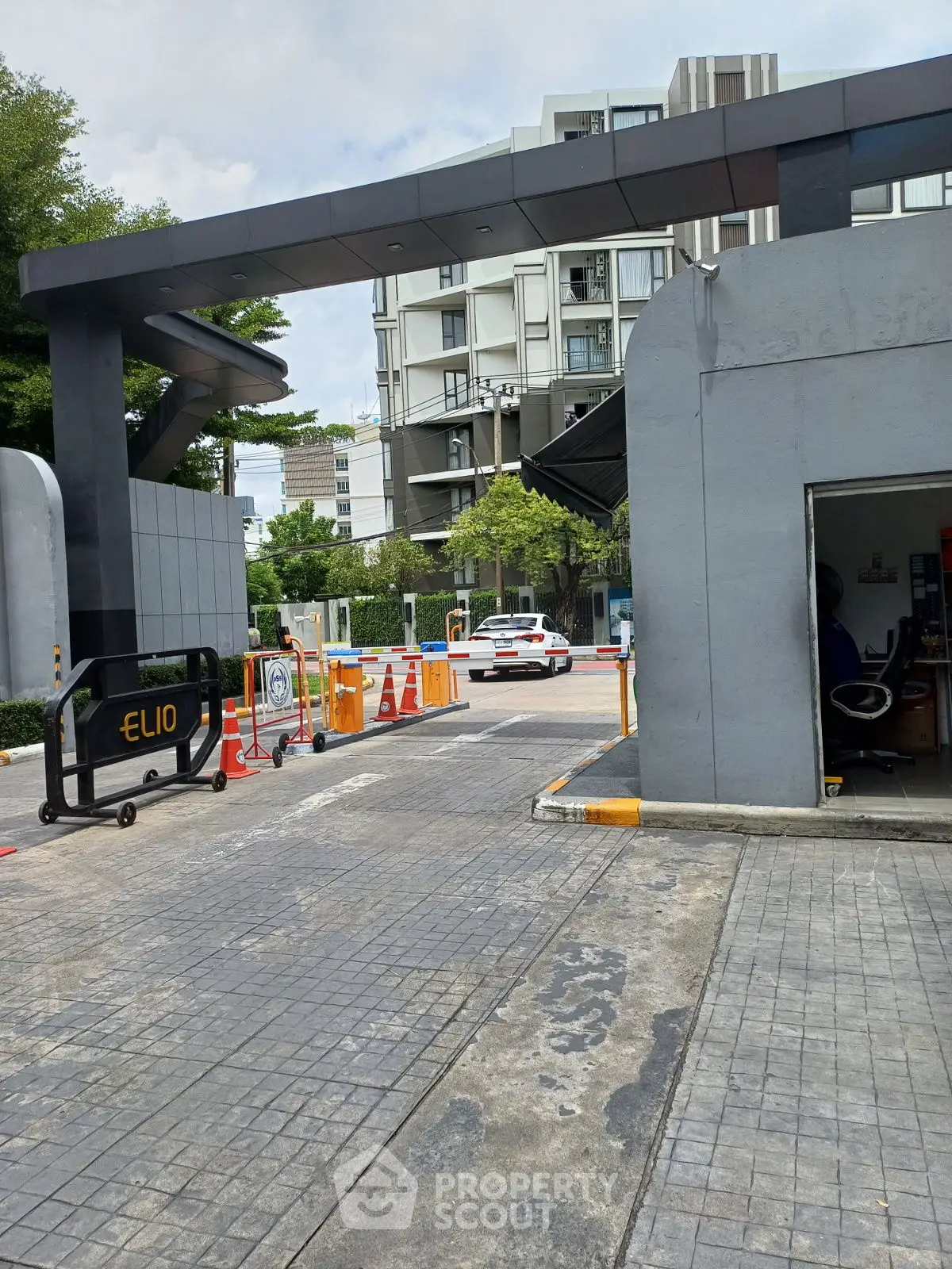Modern residential building entrance with security gate and parking area