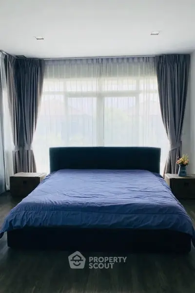 Spacious bedroom with large windows and elegant curtains