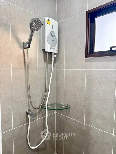 Modern bathroom with sleek shower and water heater in tiled corner.
