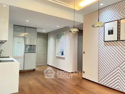 Modern open-layout kitchen with stylish lighting and wooden flooring in a contemporary apartment.