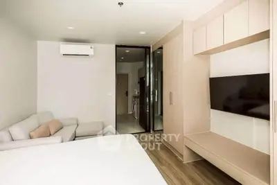 Modern bedroom with sleek design, featuring a cozy sofa, wall-mounted TV, and stylish wooden flooring.