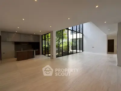 Spacious modern living room with open kitchen and large windows overlooking garden.