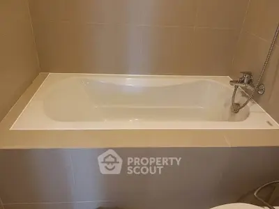 Modern bathroom with sleek bathtub and neutral tile design.