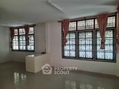 Spacious living room with large windows and elegant curtains, perfect for natural light.