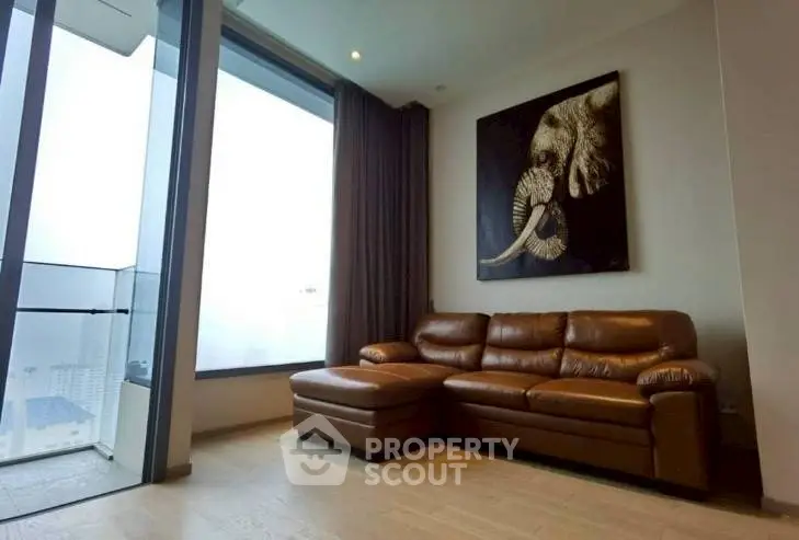Luxurious living room with leather sofa and stunning city view from balcony.