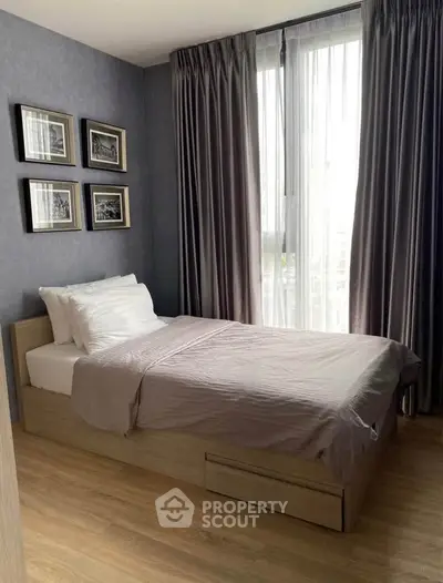 Cozy bedroom with single bed and elegant decor, featuring floor-to-ceiling window and stylish curtains.