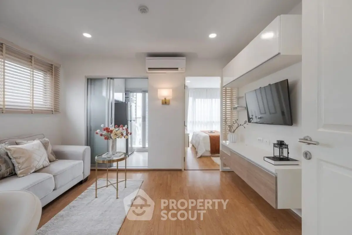 Modern living room with open layout leading to a cozy bedroom, featuring stylish decor and natural light.