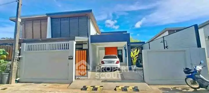 Modern house exterior with sleek design and carport, featuring a vibrant orange accent door.