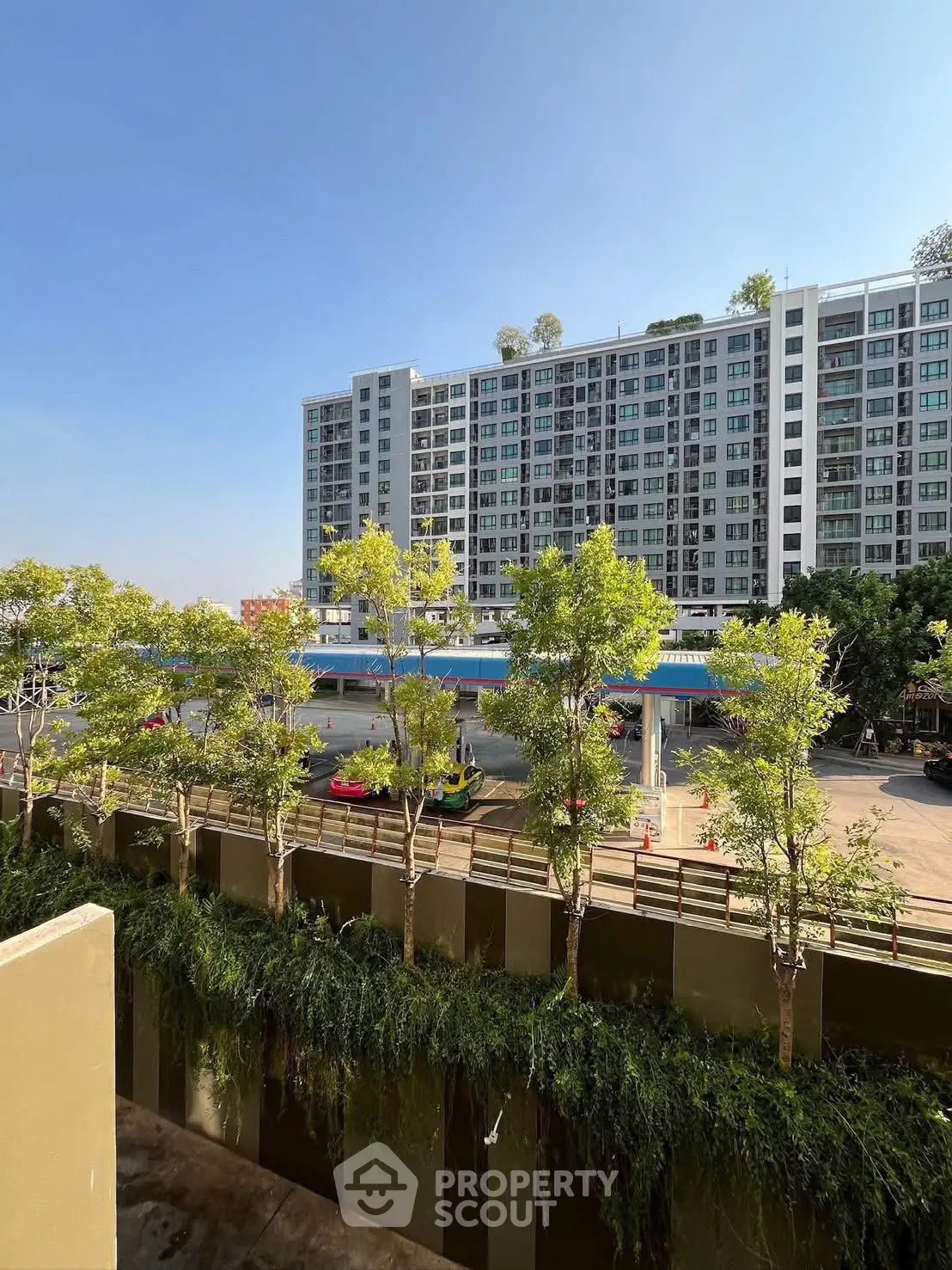 Modern apartment building with lush greenery and clear blue sky view.