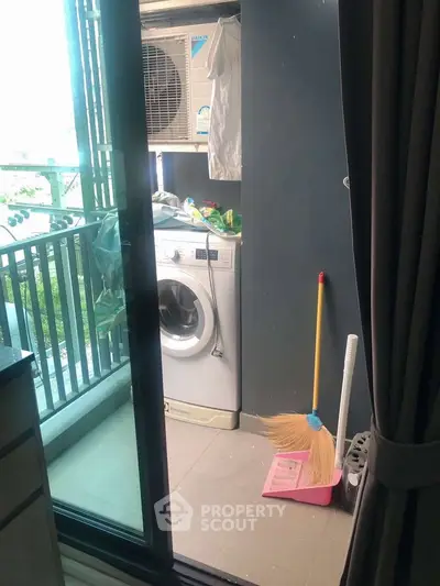 Compact balcony with washing machine and cleaning tools, ideal for urban living convenience.