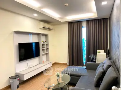 Modern living room with sleek furniture and large TV in a stylish apartment.