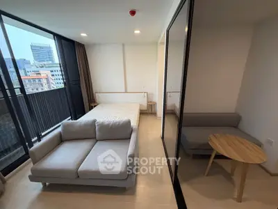 Modern studio apartment with cozy living area and city view balcony.
