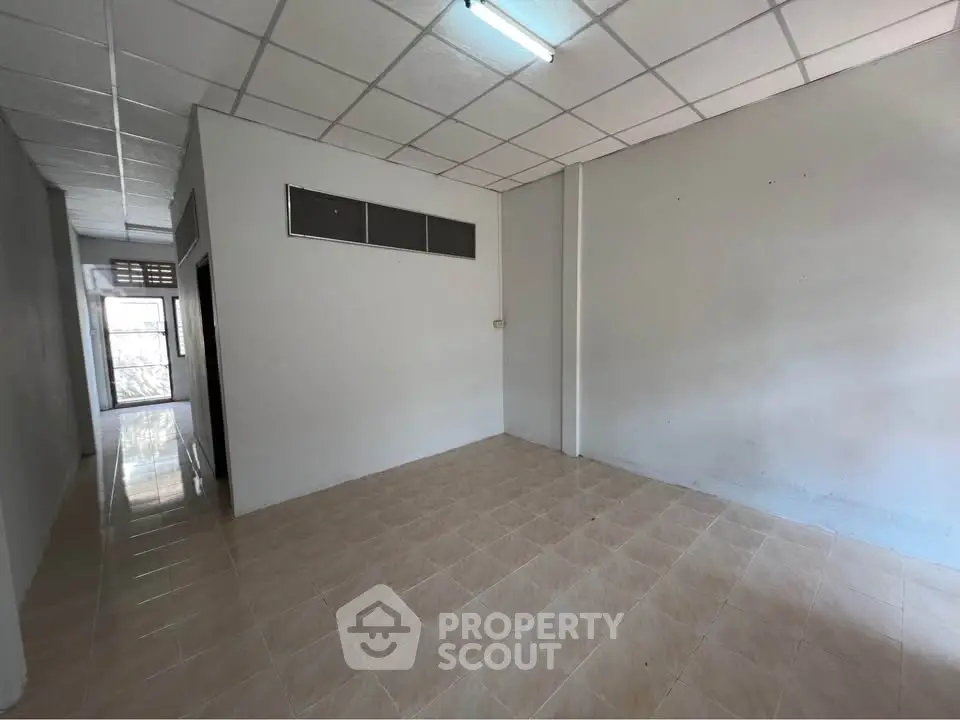 Spacious empty room with tiled floor and fluorescent lighting