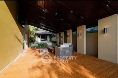 Spacious covered patio with stylish outdoor furniture and wooden deck, perfect for relaxation and entertaining.